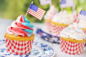 Cupcakes with red-white-and-blue frosting and American flags