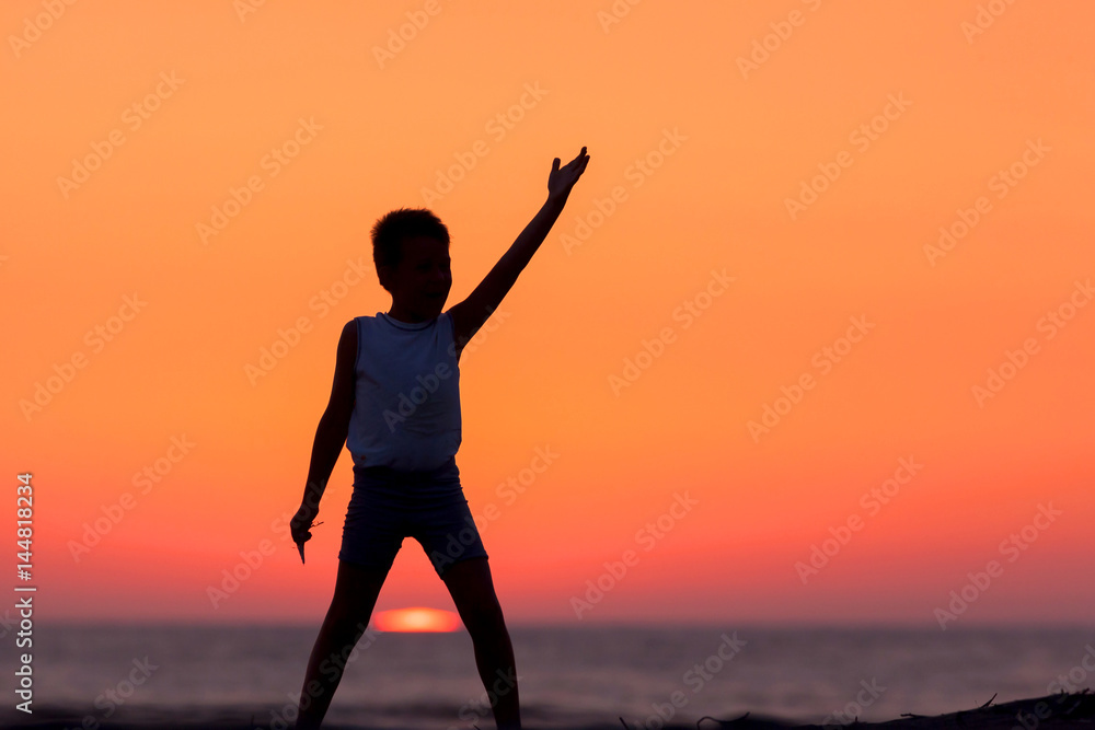Fototapeta premium A Silhouette Of A Child Playing Near The Beach At Sunset