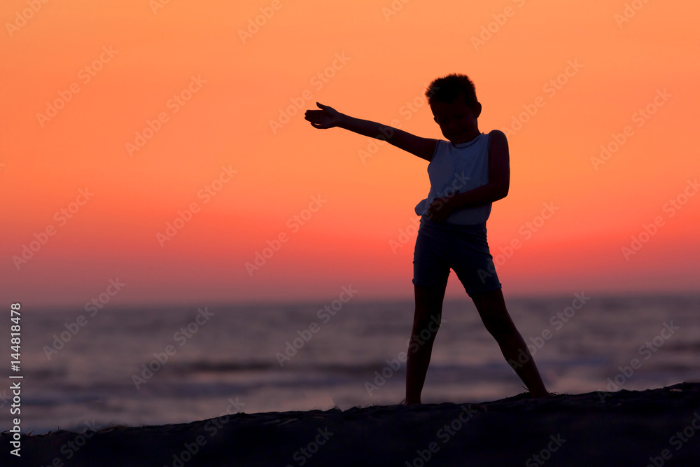 A Silhouette Of A Child Playing Near The Beach At Sunset