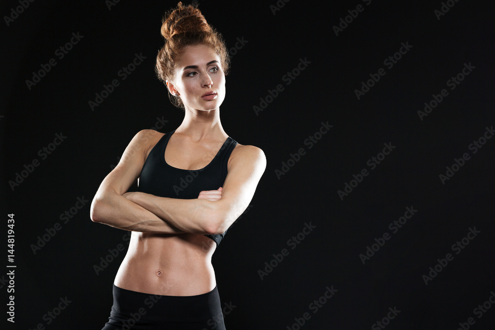 Fototapeta premium Serious young sports lady posing with arms crossed