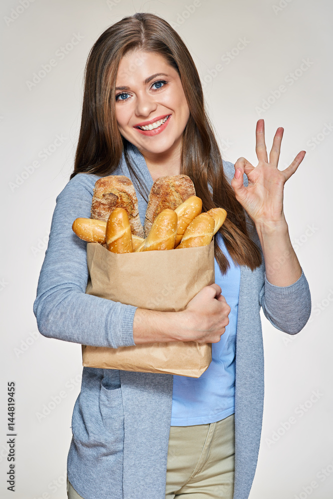 Smiling woman holding paper bag with bread shows OK Smiling woman holding paper bag with bread shows OK