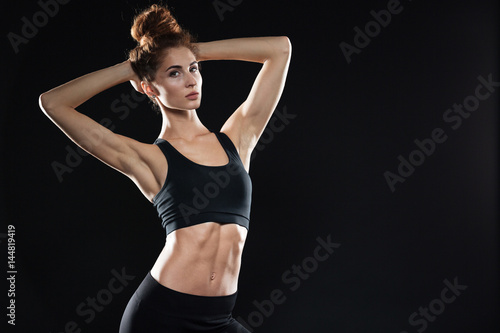 Concentrated young sports lady standing over black background