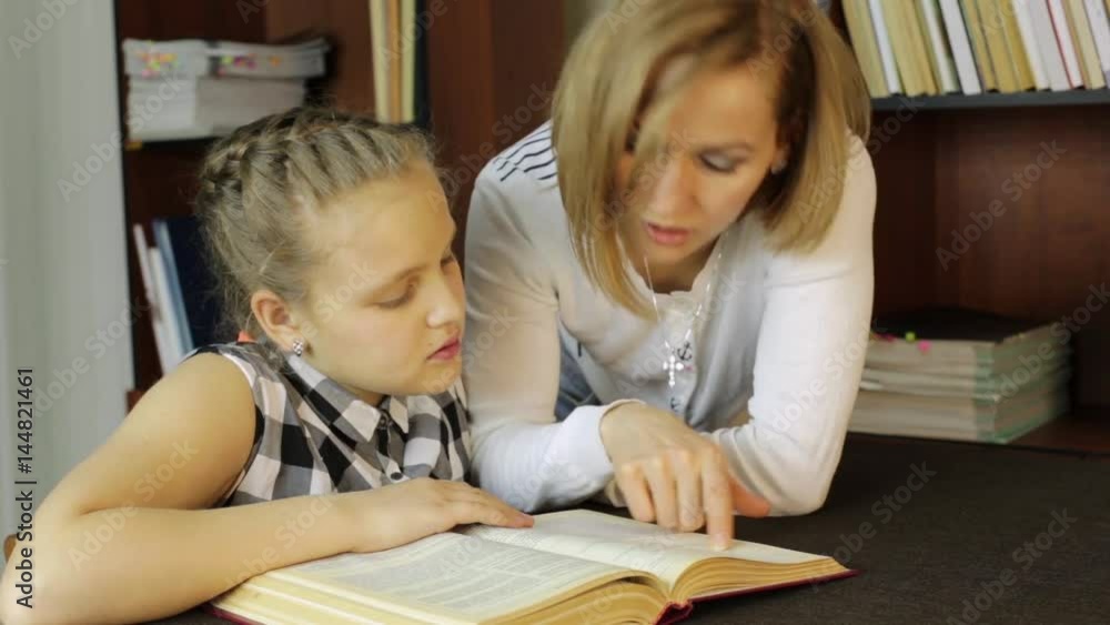 mother helping her daughter do homework. Girl makes lessons, reading mother helping her daughter do homework. Girl makes lessons, reading