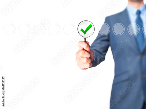 Businessman magnifying glass check mark on virtual screen.