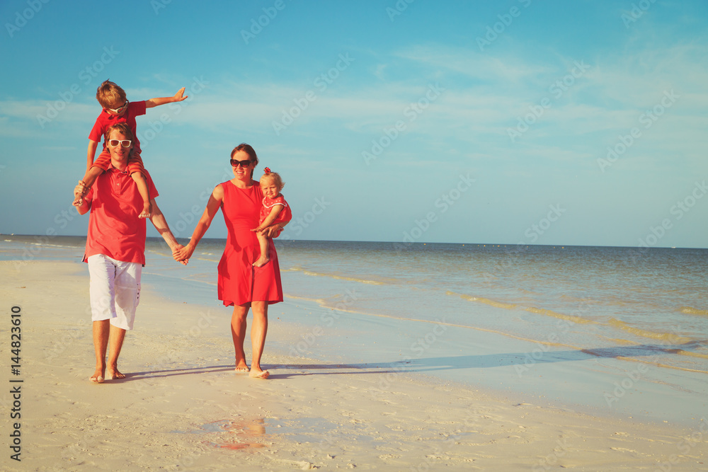Happy family with two kids walking at beach