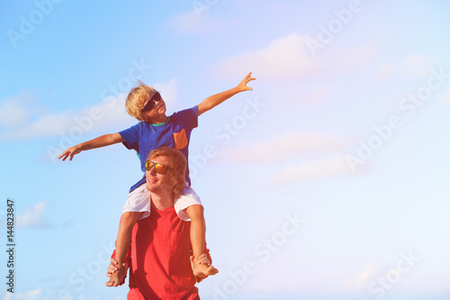 Father and little son playing on blue sky