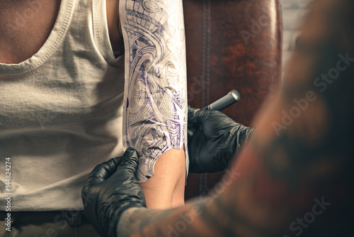 Tattoo master putting ornament on female arm