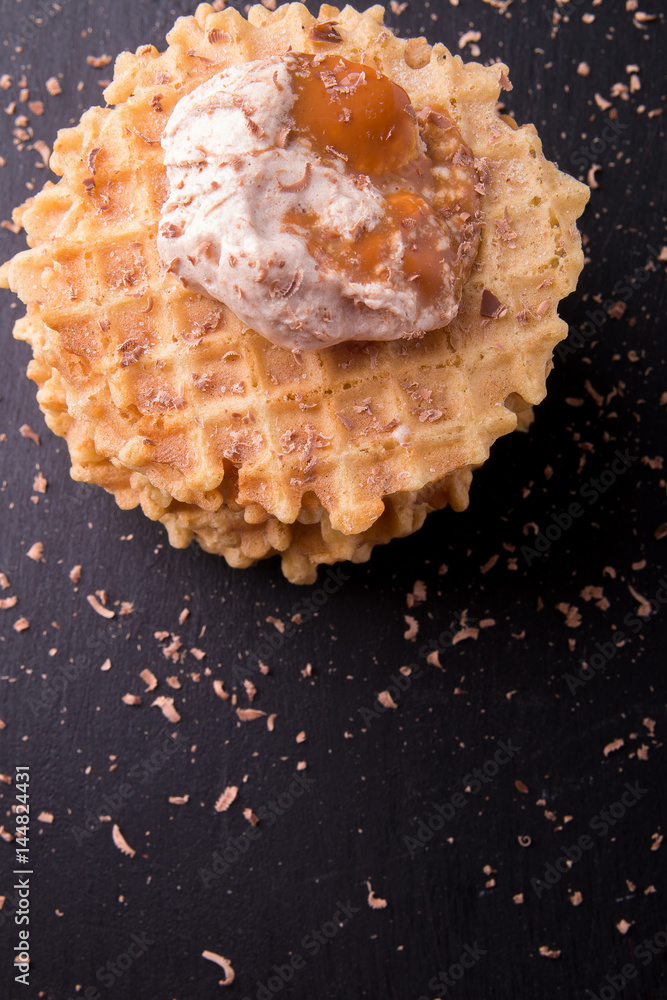 Belgian waffle with ice cream and chocolate on black background. Top view. Belgian waffle with ice cream and chocolate on black background. Top view.