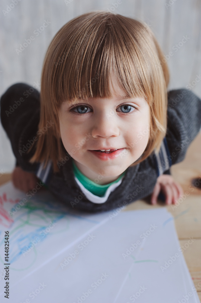 cute toddler boy drawing at home with colored pencils