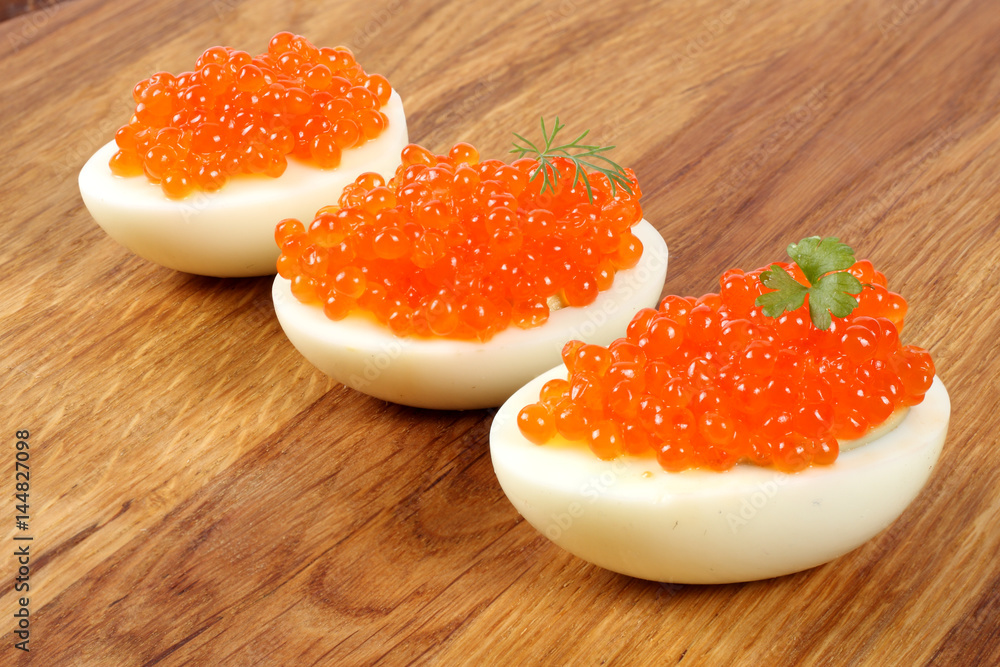 Red caviar on eggs on wood background Red caviar on eggs on wood background