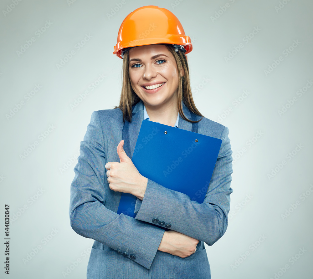Smiling businesswoman wearing safety helmet holding clipboard Smiling businesswoman wearing safety helmet holding clipboard