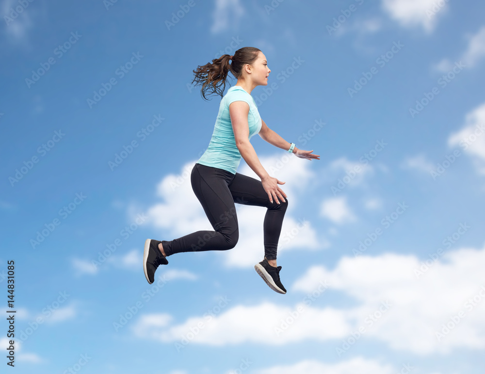 Fototapeta premium happy smiling sporty young woman jumping in air