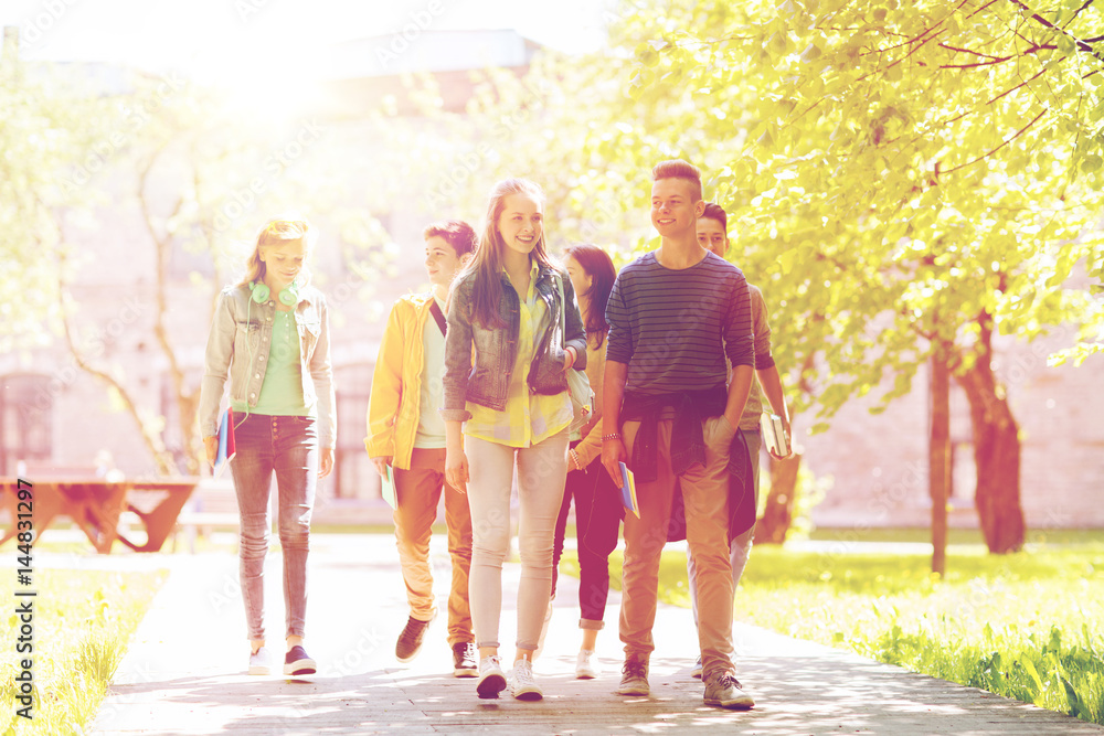 Naklejka premium group of happy teenage students walking outdoors