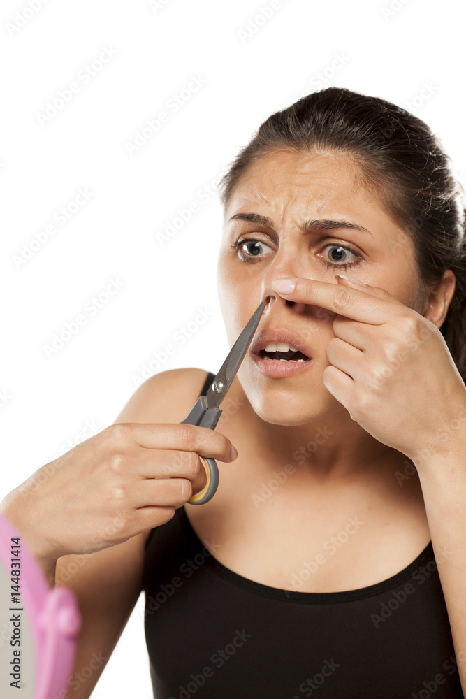 young woman removes hair from her nose using scissors young woman removes hair from her nose using scissors