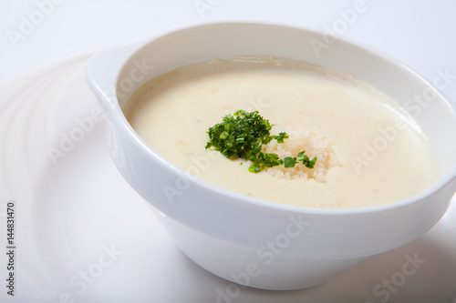 delicious creamy soup with parsley and cheese on white dish