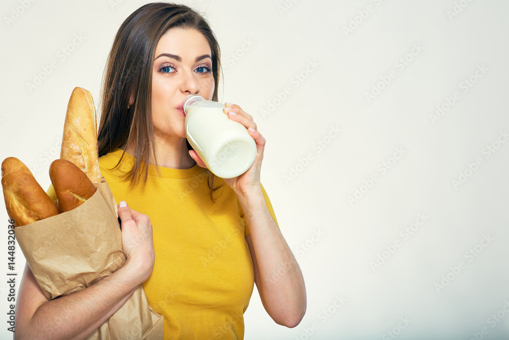Young woman drinking milk hold paper bag with bread. Young woman drinking milk hold paper bag with bread.