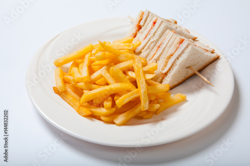 Club sandwiches with chicken and french fries on a white plate