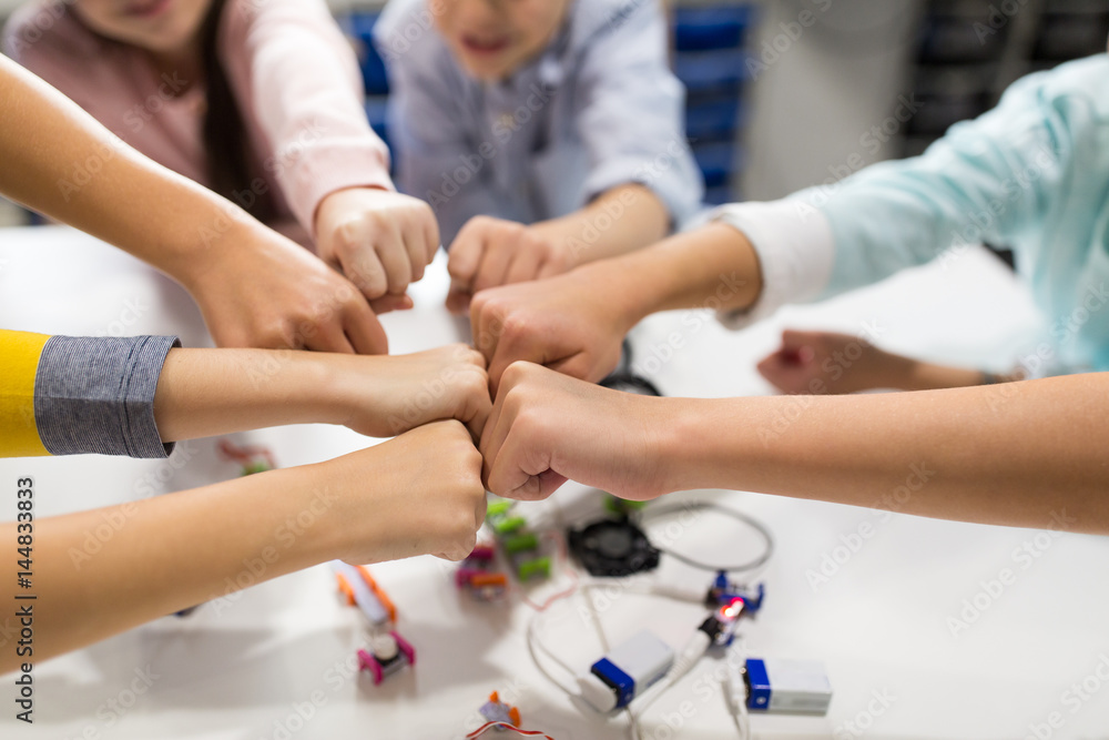Obraz premium happy children making fist bump at robotics school