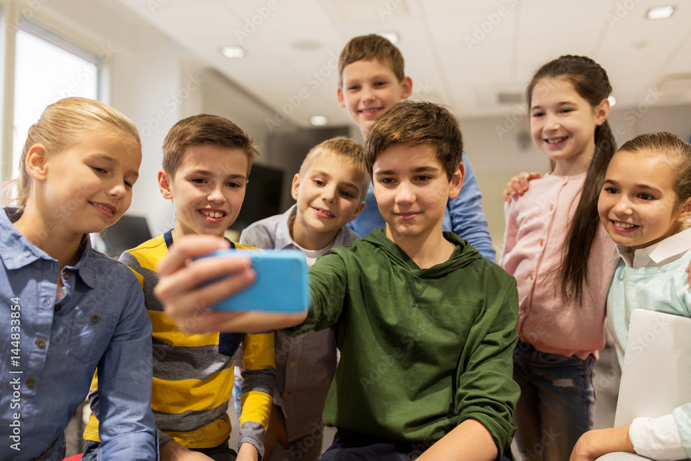 Obraz premium group of school kids taking selfie with smartphone