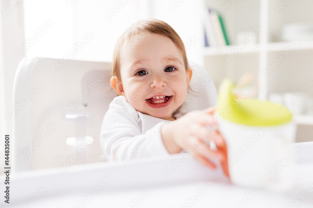 baby drinking from spout cup in highchair at home baby drinking from spout cup in highchair at home