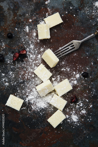 Square pieces of white gourmet chocolate on rustic background