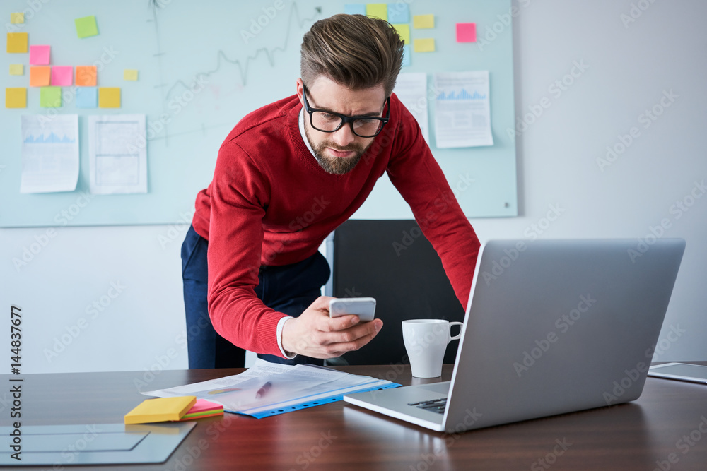 Unhappy businessman reading bad news on his phone Unhappy businessman reading bad news on his phone