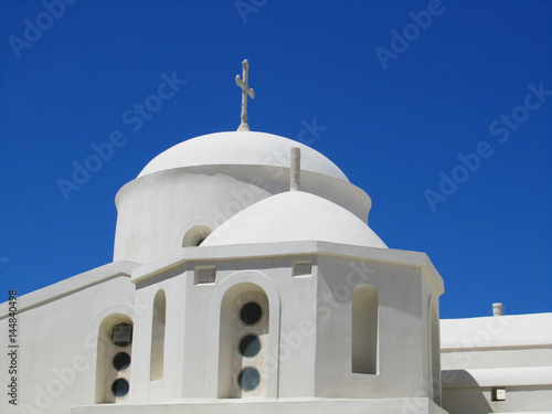 A white church in the main city of Naxos island, Greece, with blue sky in the background.