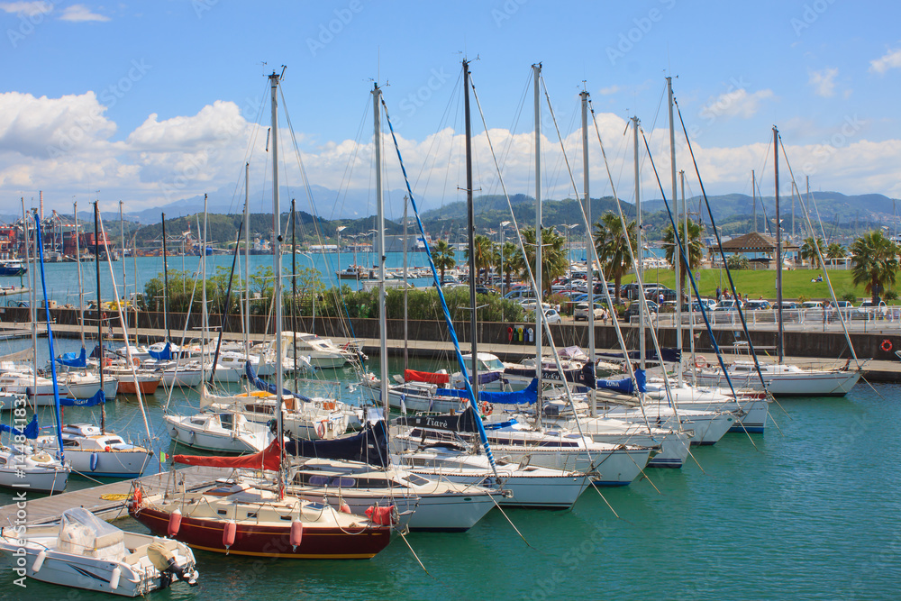 Yacht parking. Italian Riviera. Different yachts on the background of the sea and the city. The mountains