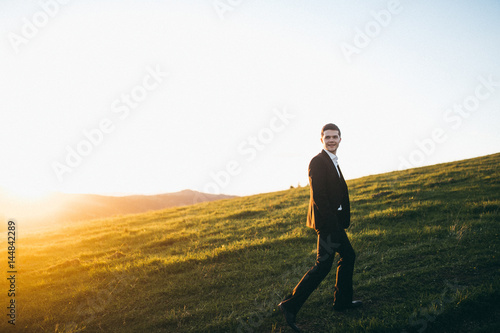 Handsome groom on sunset in the mountains