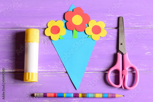 Making paper crafts for mother's day or birthday. Step. Paper flowers bouquet, scissors, glue stick, pencil on a wooden table. Set for kids creativity at home or in kindergarten. Top view