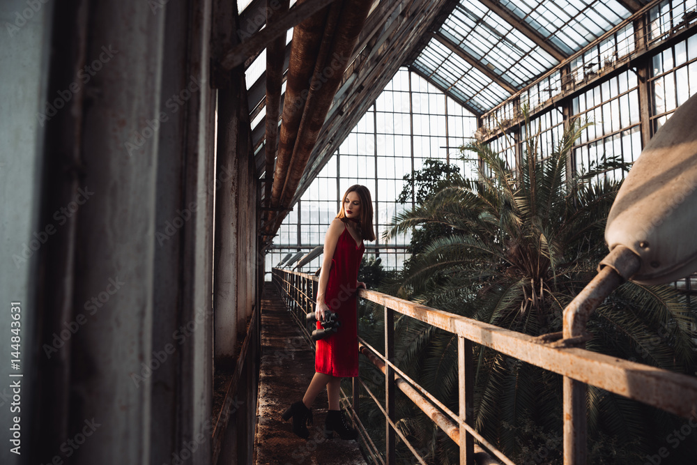 Woman in red dress with binoculars standing at greenhouse