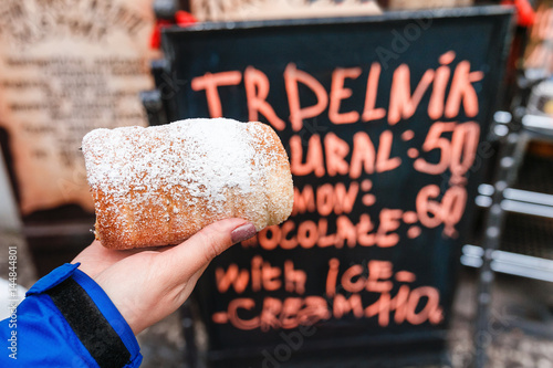 Photography Woman hand closeup holding traditional czech sweet street food trdelnik On a bac