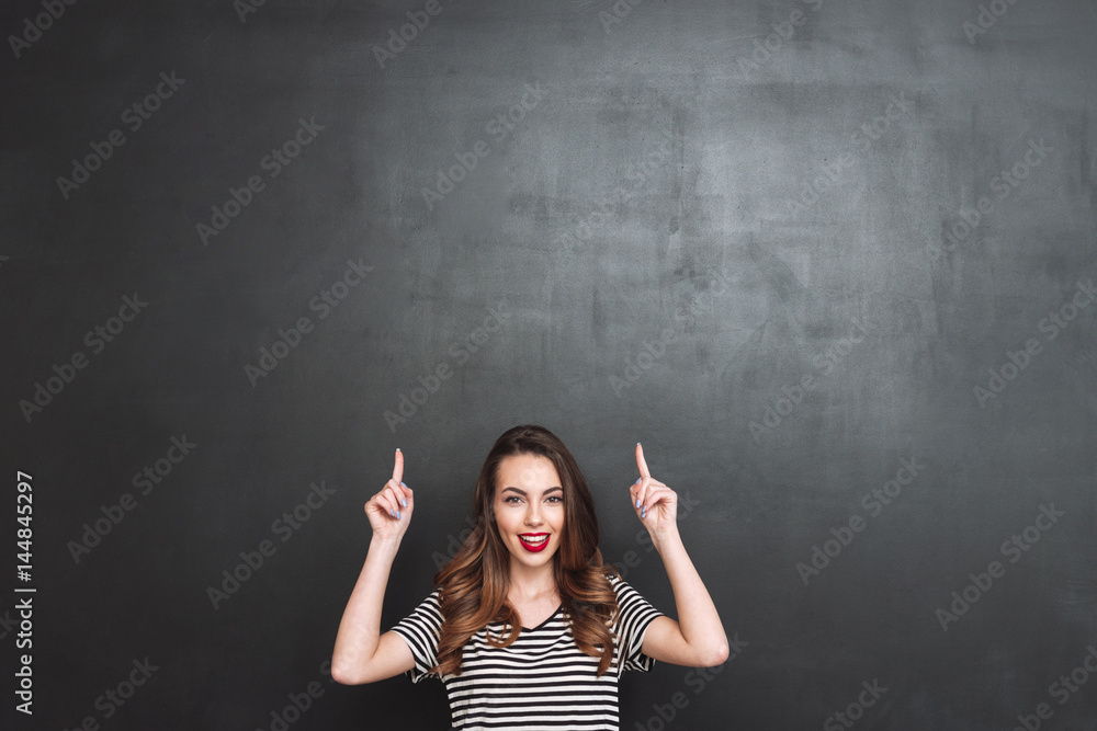 Smiling woman looking at camera and pointing up Smiling woman looking at camera and pointing up