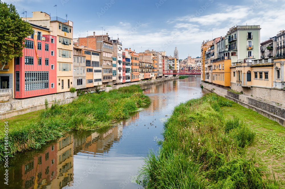 Cloudy view of riverside and bridge over river Onyar, Girona, Catalonia, Spain.
