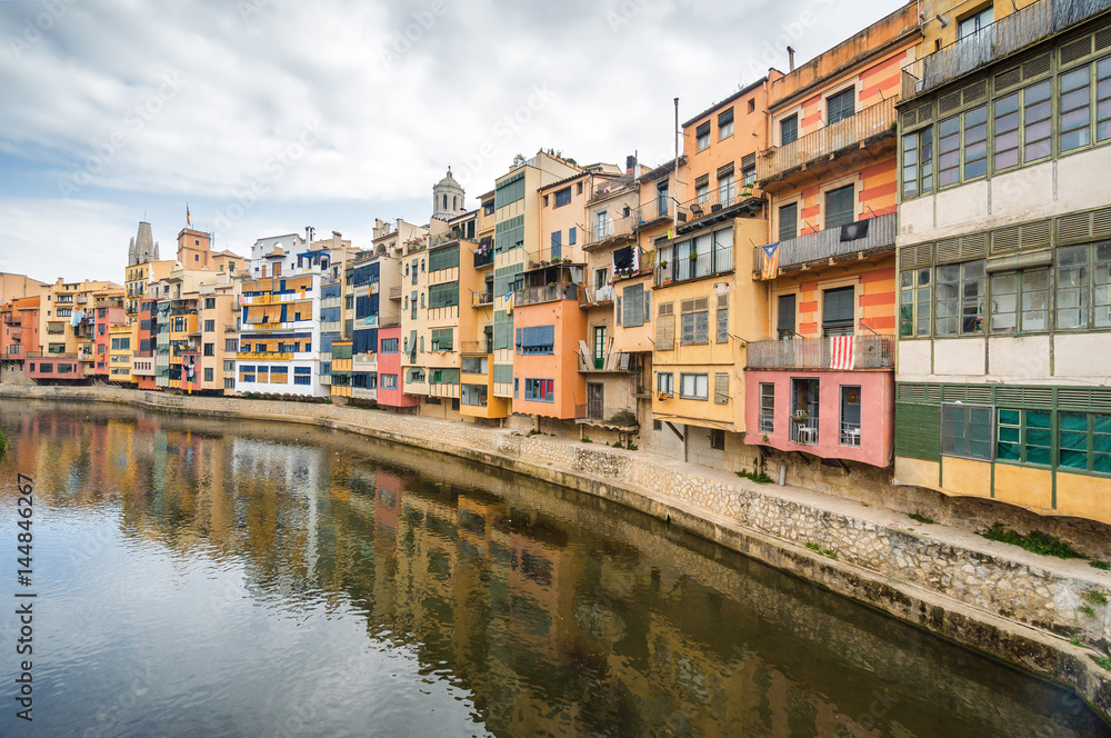 Cloudy view of riverside and bridge over river Onyar, Girona, Catalonia, Spain.