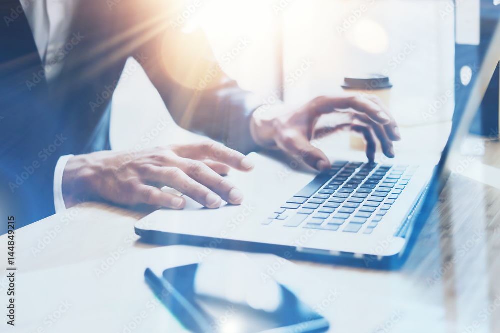 Young businessman working at sunny office on laptop.Man pointing notebook keyboard.Blurred background.Sunlight effects. Young businessman working at sunny office on laptop.Man pointing notebook keyboard.Blurred background.Sunlight effects.