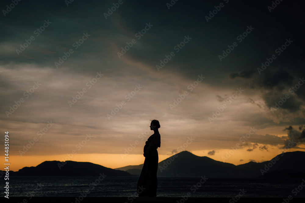 Silhouette of a pregnant woman at sunset by the sea Montenegro