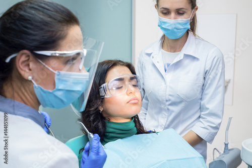 Dentists working at the office. Patient wearing dental safety glasses.