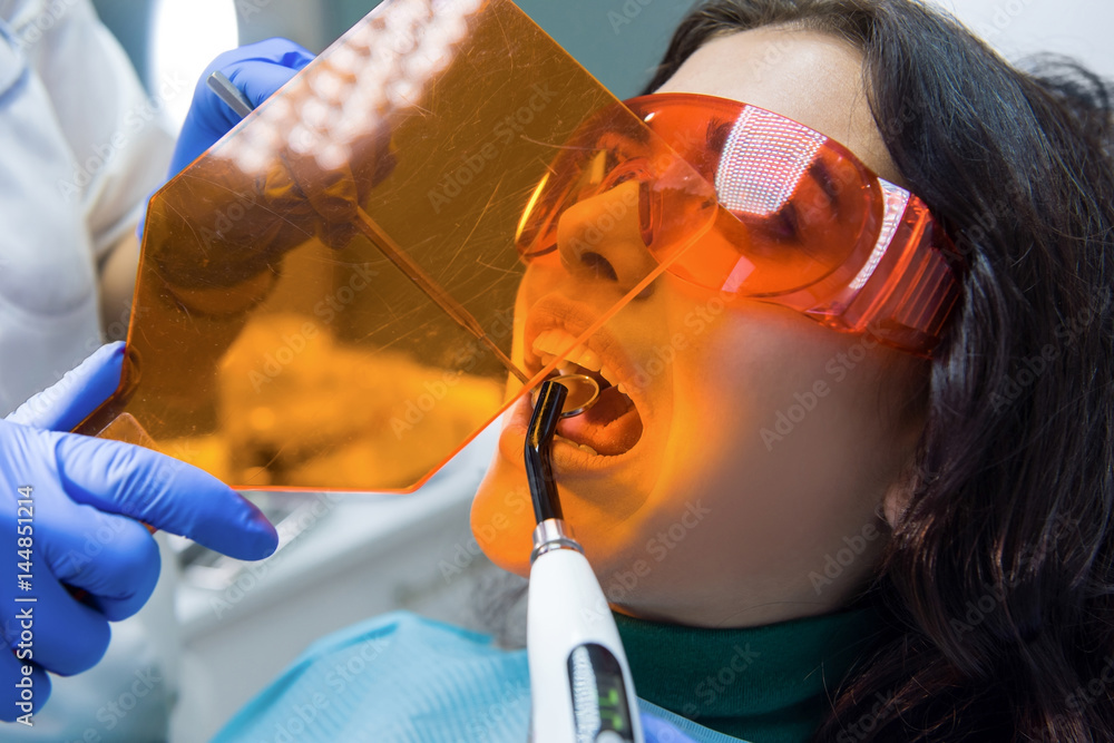 Female patient at the dentist. Concave mirror and curing light. Stock