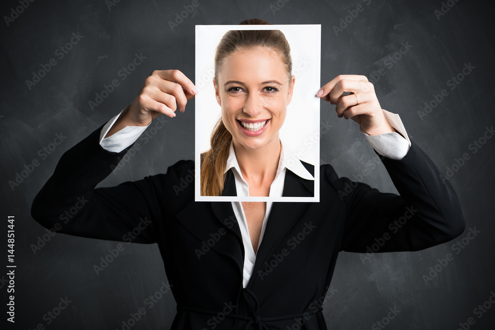 junge Geschäftsfrau hält Schild mit lächelndem Portrait vor ihr Gesicht junge Geschäftsfrau hält Schild mit lächelndem Portrait vor ihr Gesicht