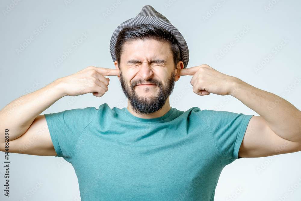 Annoyed young man plugging ears with hands Annoyed young man plugging ears with hands