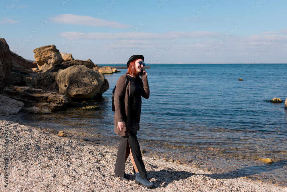 Woman calling by cell phone and walking on beach.