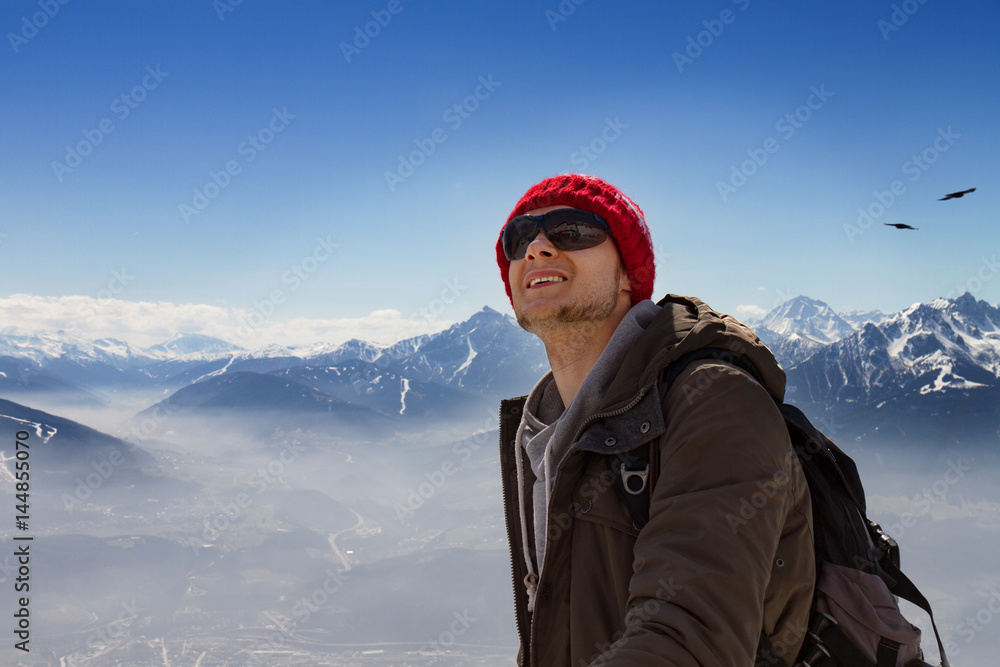 Young hiking man sportsman or traveler with backpack staying and looking on horizon.Travel or Sport Concept.