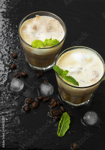 Fresh coffee drinks frappes with froth in transparent glasses with coffee beans and ice cubes,top view