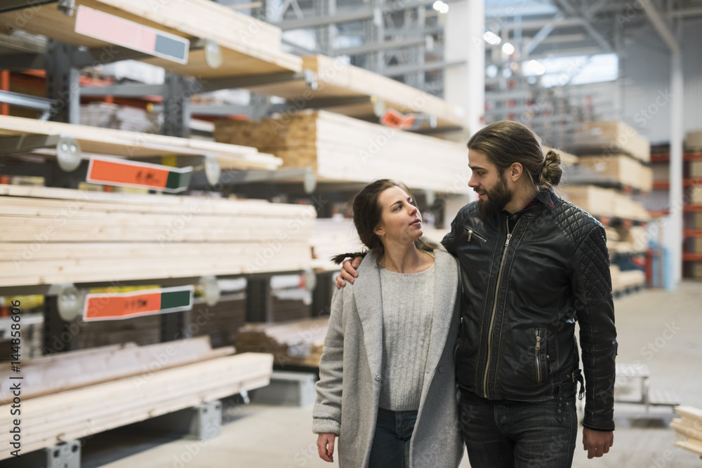 Couple looking at each other while walking in hardware store warehouse Couple looking at each other while walking in hardware store warehouse