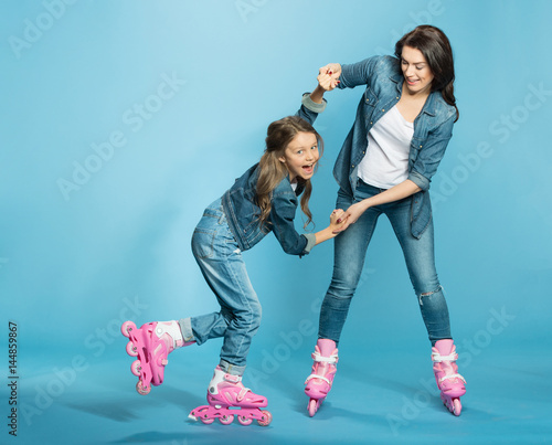 Bilde på lerret mother and daughter in roller skates having fun in studio on blue