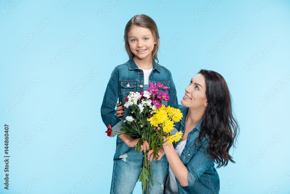 happy mother and daughter hugging and holding flowers in studio on blue, Happy mothers day happy mother and daughter hugging and holding flowers in studio on blue, Happy mothers day