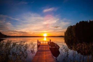 Fotobehang Pier Vissteiger Fins meer in avondgloed  © NBLX