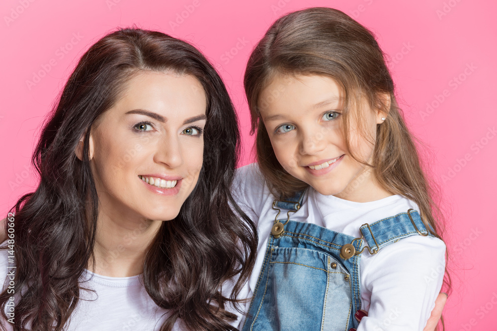 Close-up portrait of beautiful happy mother and daughter hugging and smiling at camera Close-up portrait of beautiful happy mother and daughter hugging and smiling at camera