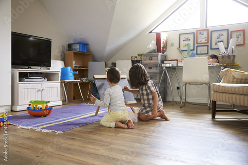 Boy And Girl Drawing On Chalkboard In Playroom